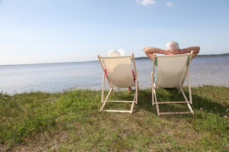 Senior couple in deck chairs in front of a lake