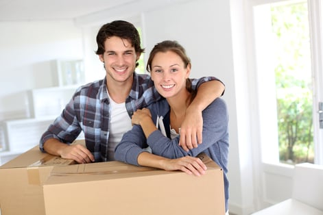 Smiling couple leaning on boxes in new home