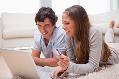 Young couple lying on the floor with laptop booking holidays